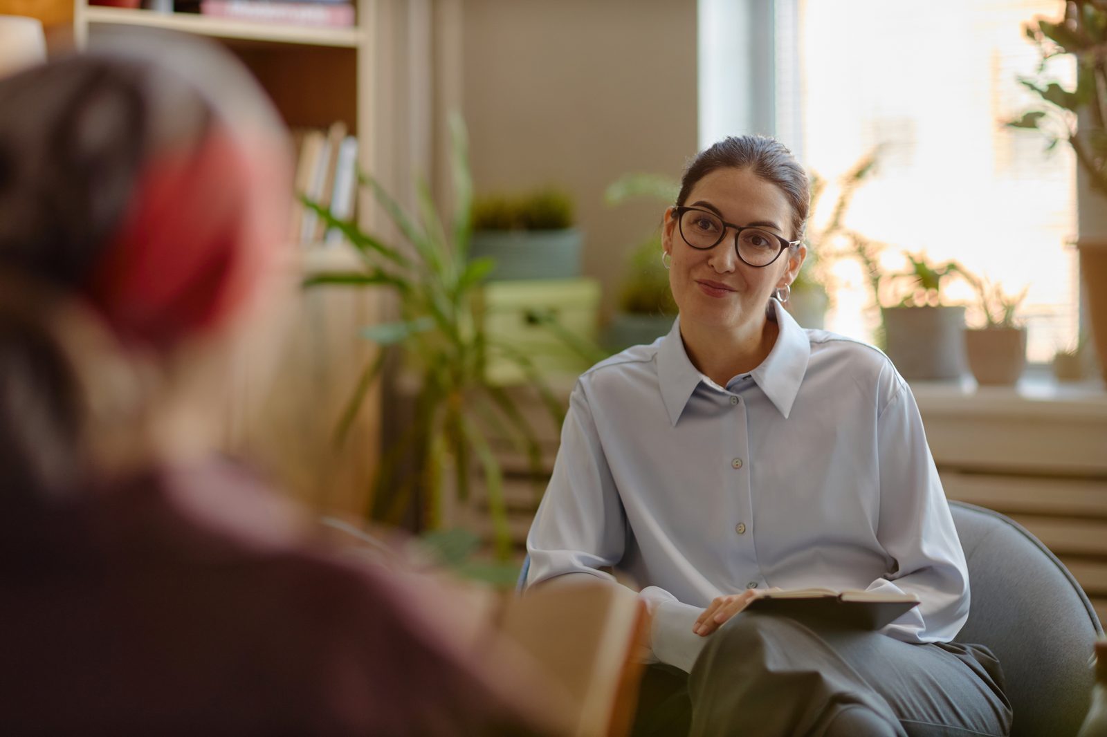 A therapist with glasses listening to a client during a session