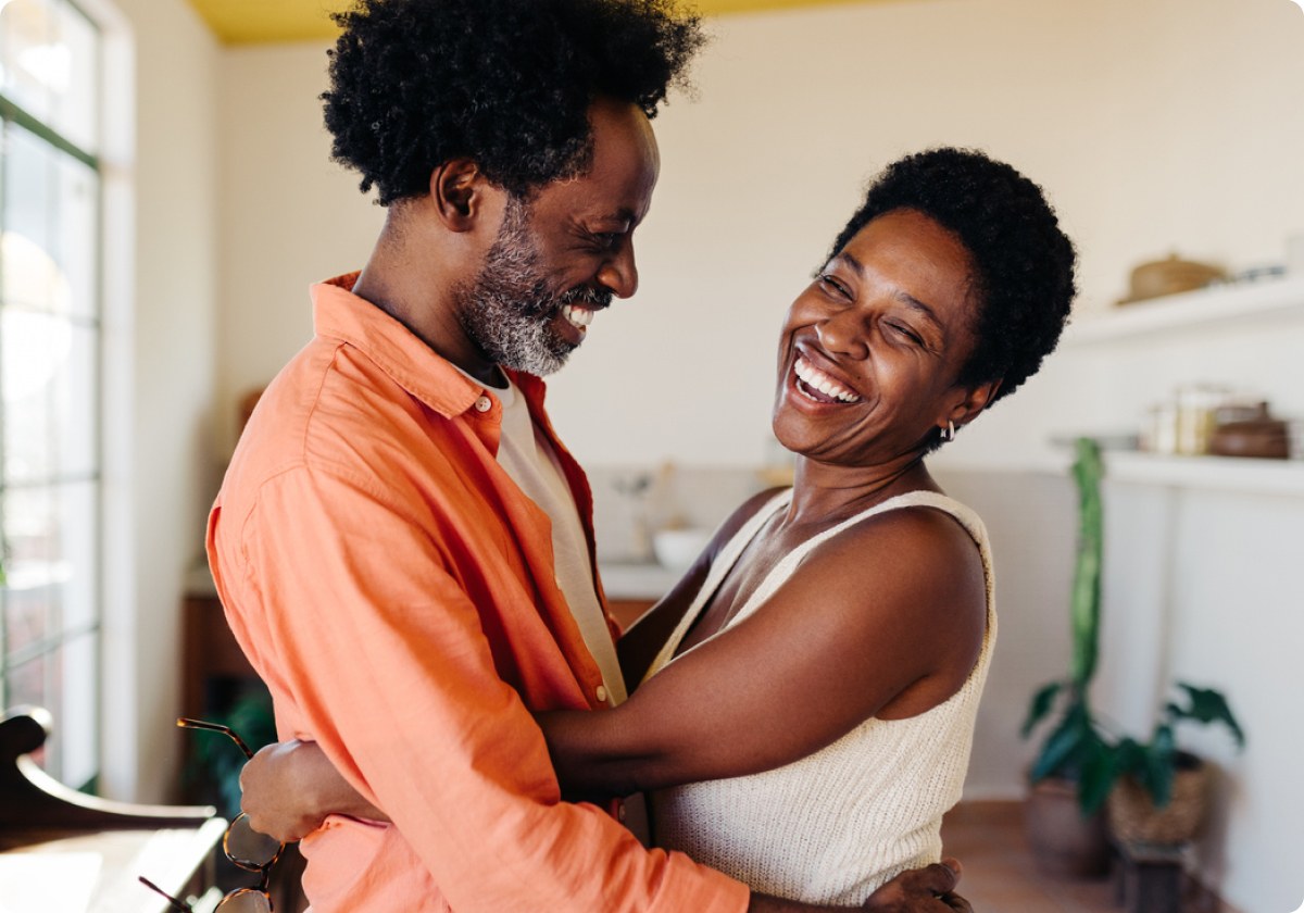 A laughing couple hugging in their living room