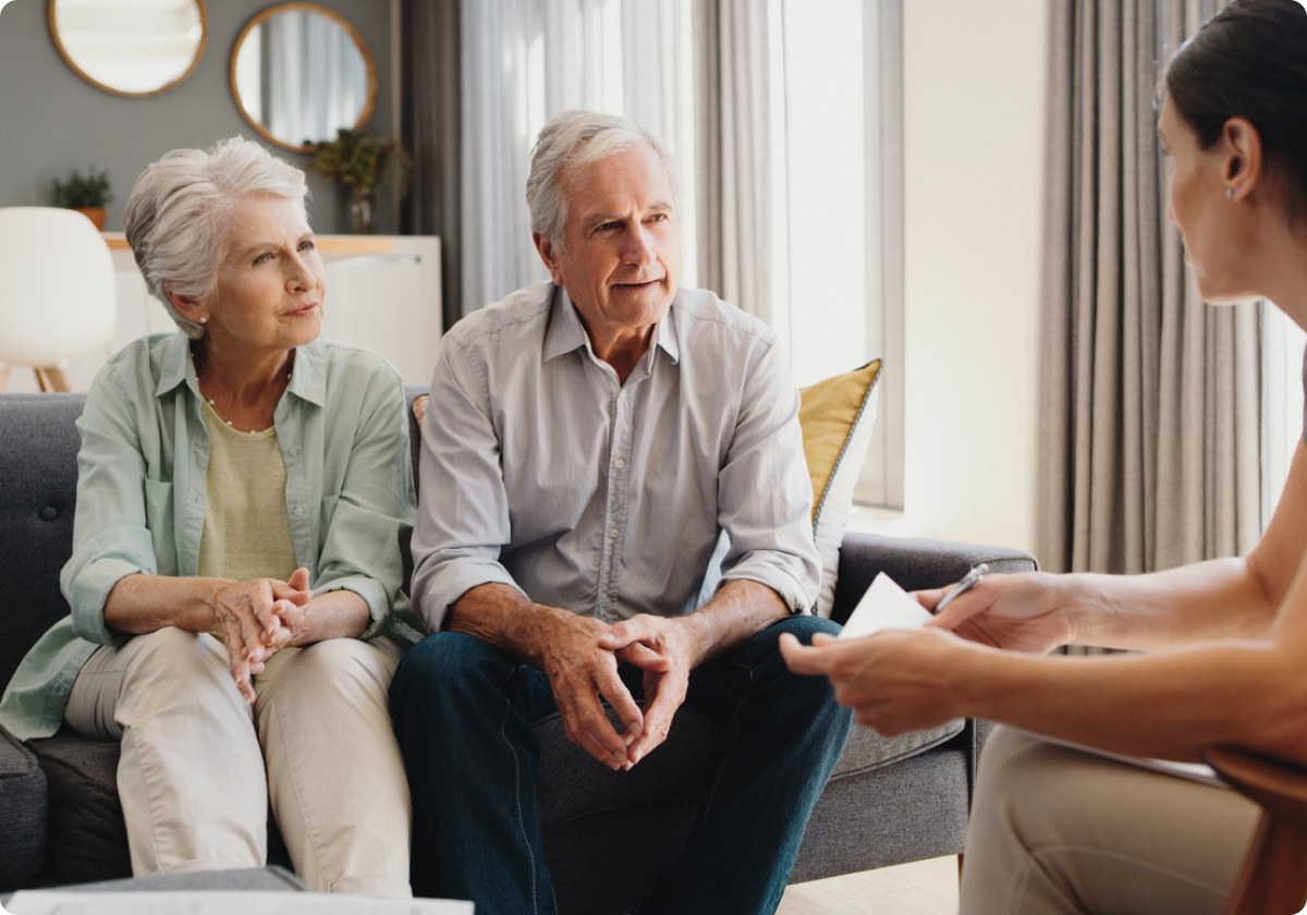 An older couple sitting together on a couch listening to their therapist